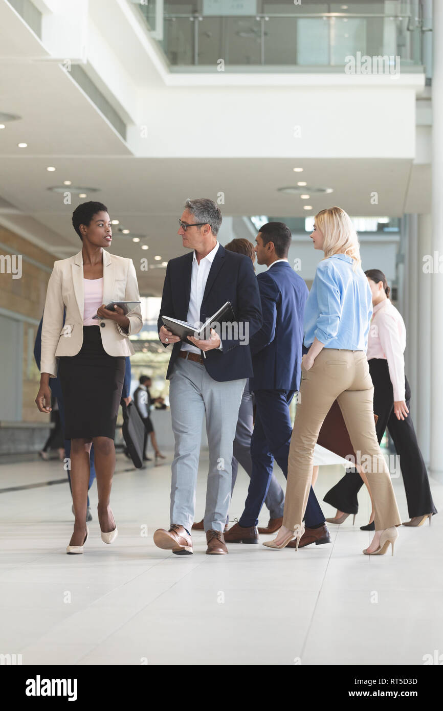 Diverse business people interacting with each other while walking in lobby office Stock Photo