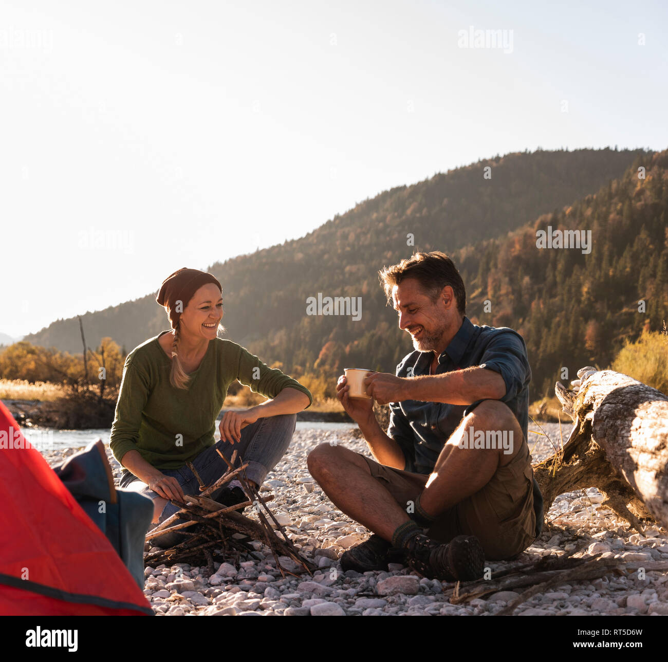 Mature couple camping at riverside in the evening light Stock Photo