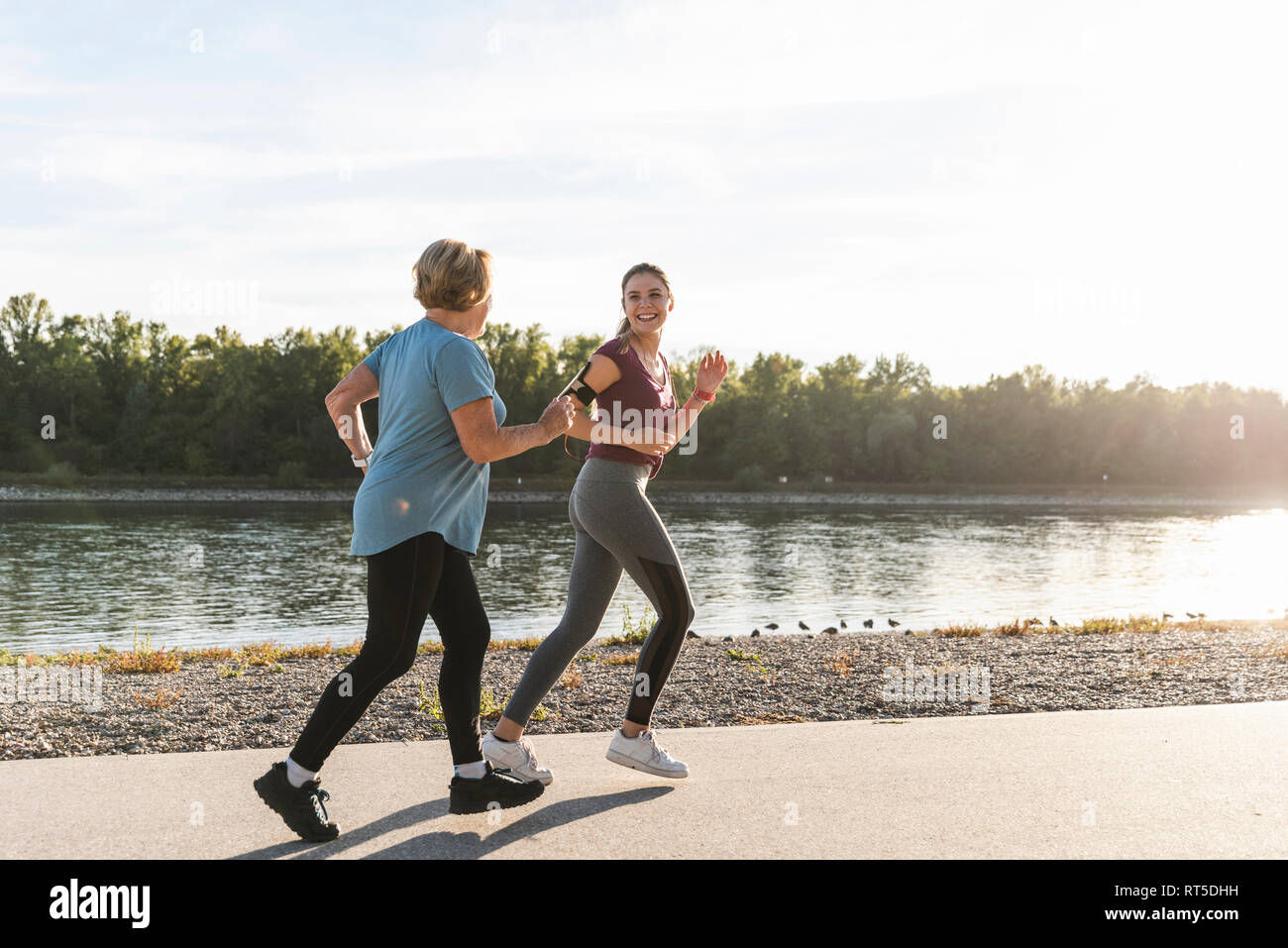 Granddaughter and grandmother having fun, jogging together at the river Stock Photo