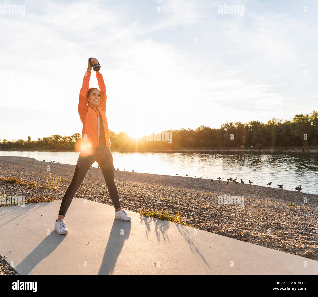 Young woman exercising with a kettlebell at the river Stock Photo