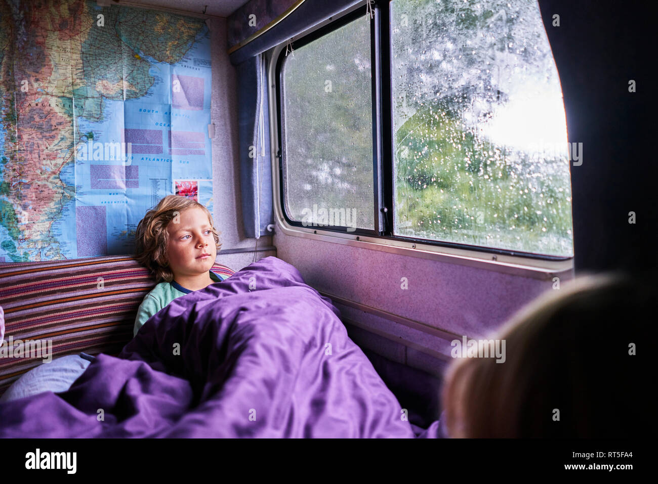 Boy in pyjama looking out of window of a camper Stock Photo