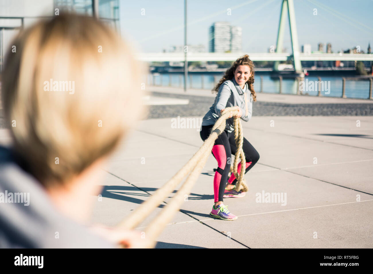 Friends training at the riverside, pulling rope Stock Photo Alamy