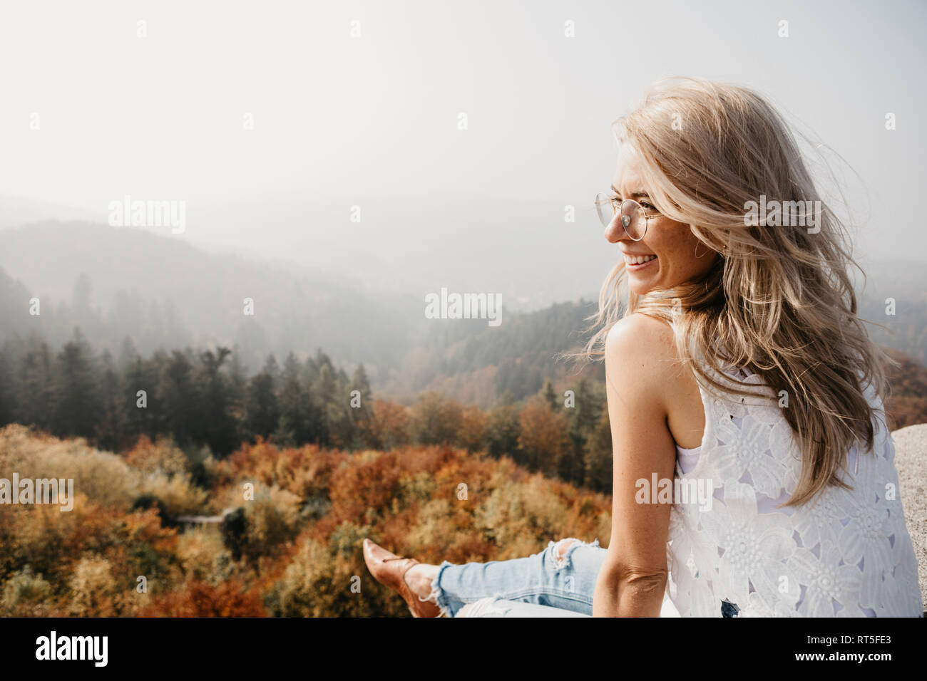 Germany, Black Forest, Sitzenkirch, smiling young woman sitting in mountain forest Stock Photo