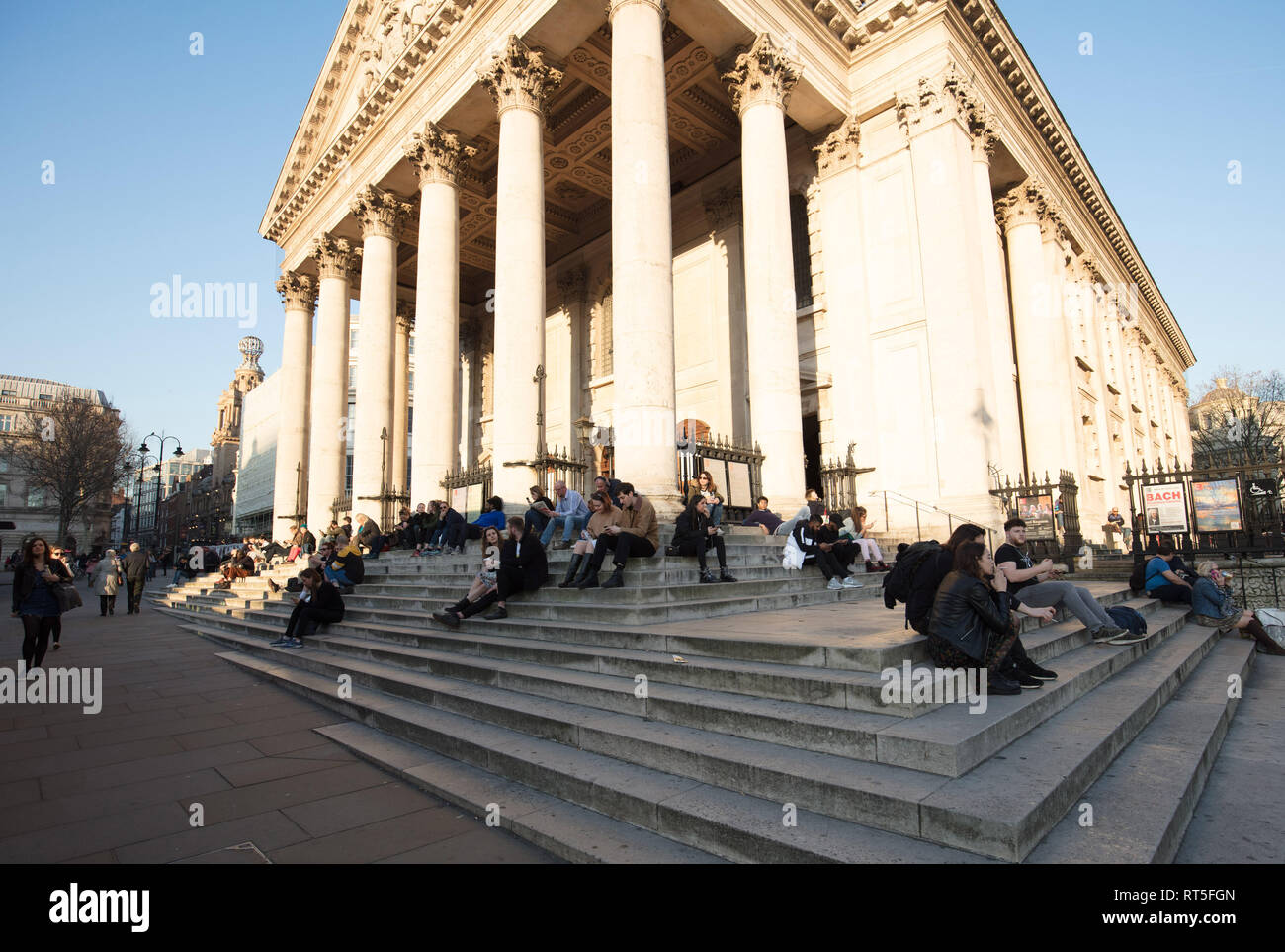 People enjoying the spring like weather on the steps of Saint Martin in the Fields Church, London, UK, this warm and sunny afternoon in February. Stock Photo