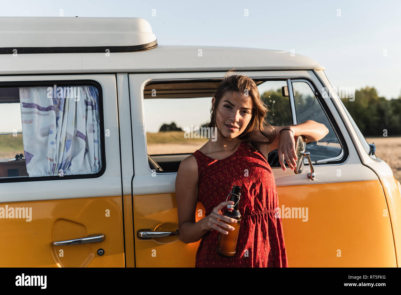 Pretty woman on a road trip with her camper, taking a break at sunset ...