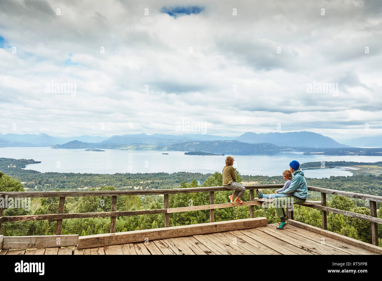 Chile, Puren, Nahuelbuta National Park, woman with two sons sitting on observation terrace overlooking the lake Stock Photo