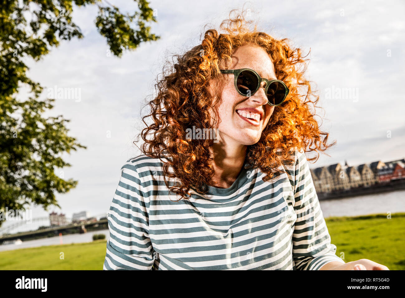 Germany, Cologne, portrait of laughing redheaded young woman wearing sunglasses Stock Photo