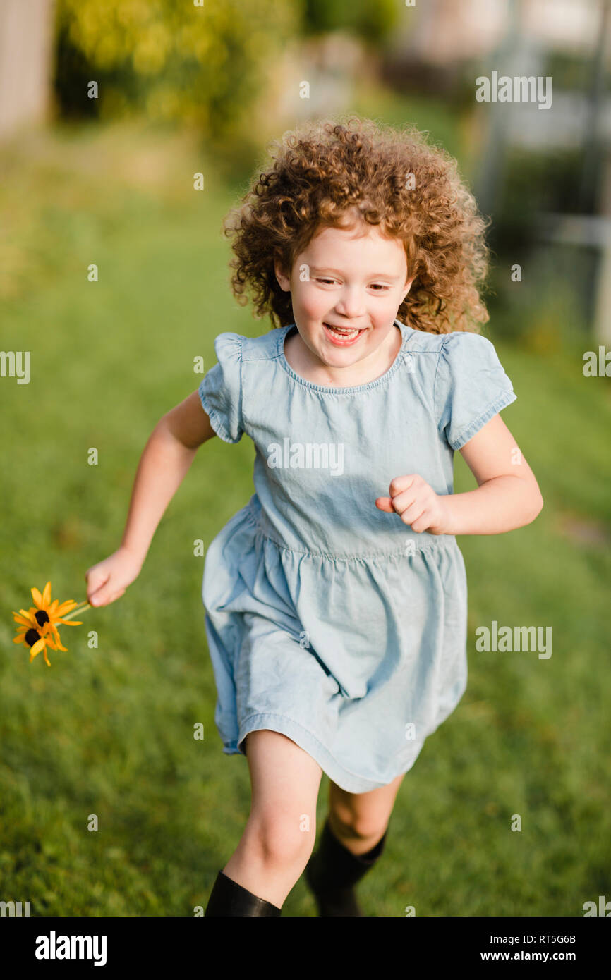 Happy little girl running on a meadow in the garden Stock Photo