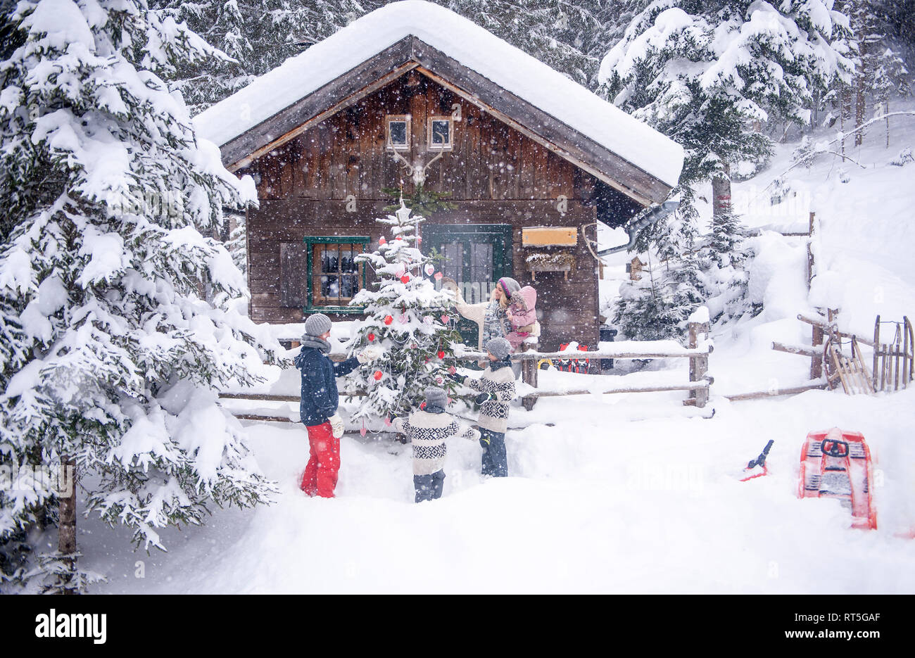 Austria, Altenmarkt-Zauchensee, family decorating Christmas tree at wooden house Stock Photo