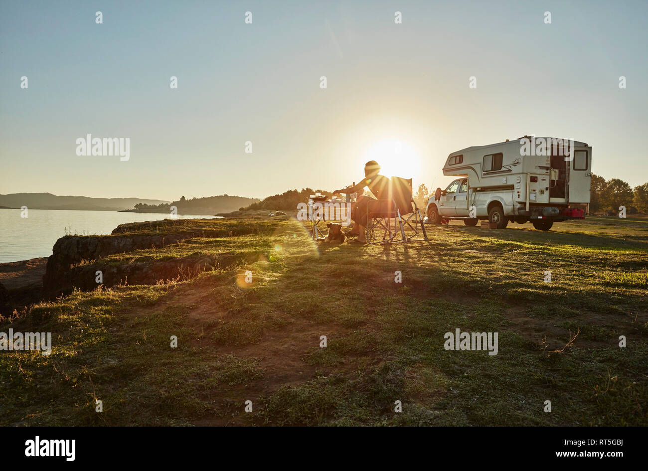 Chile, Talca, Rio Maule, camper at lake with woman and dog at sunset Stock Photo