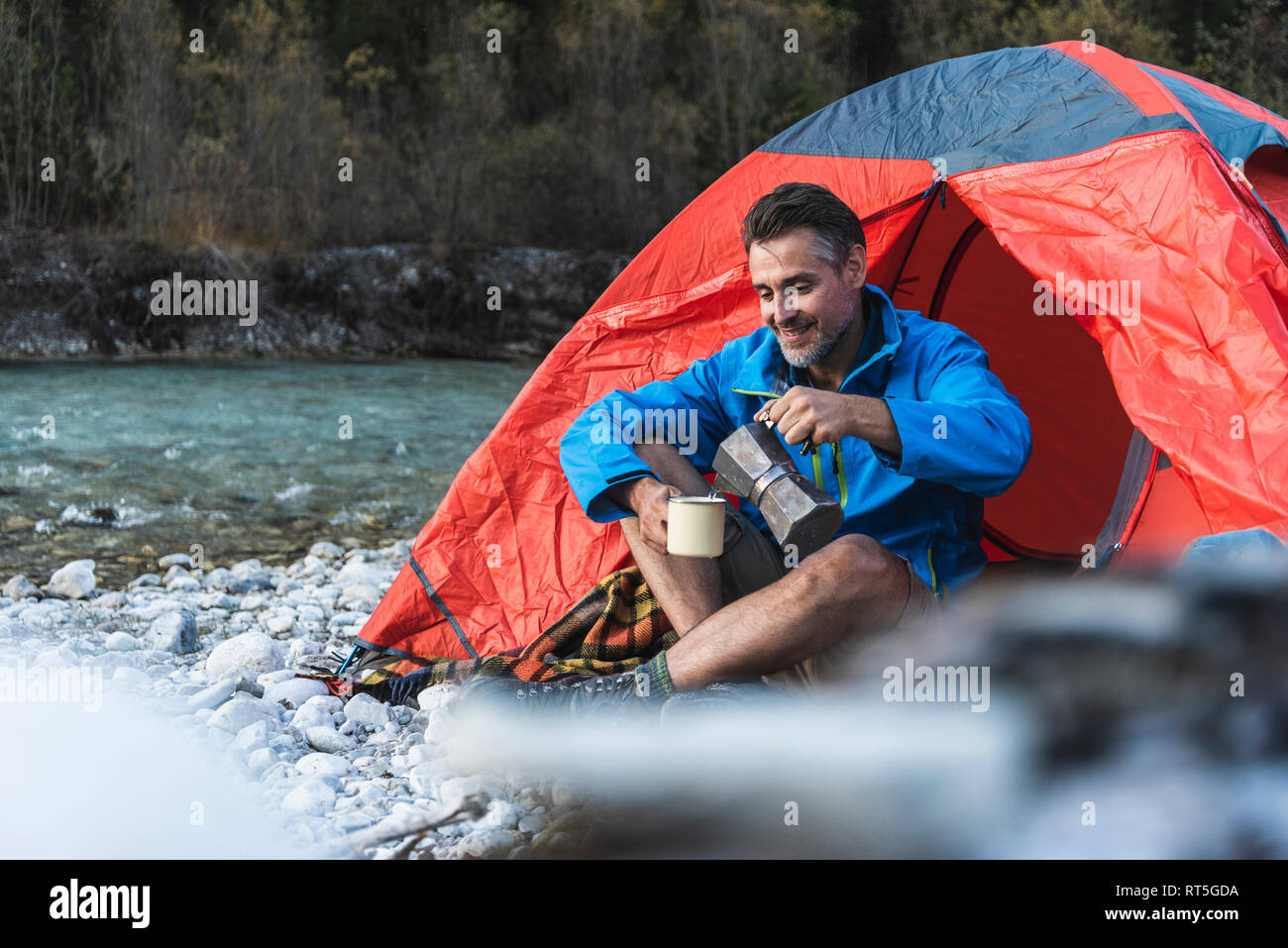 Mature man camping at riverside, espresso maker and cup Stock Photo