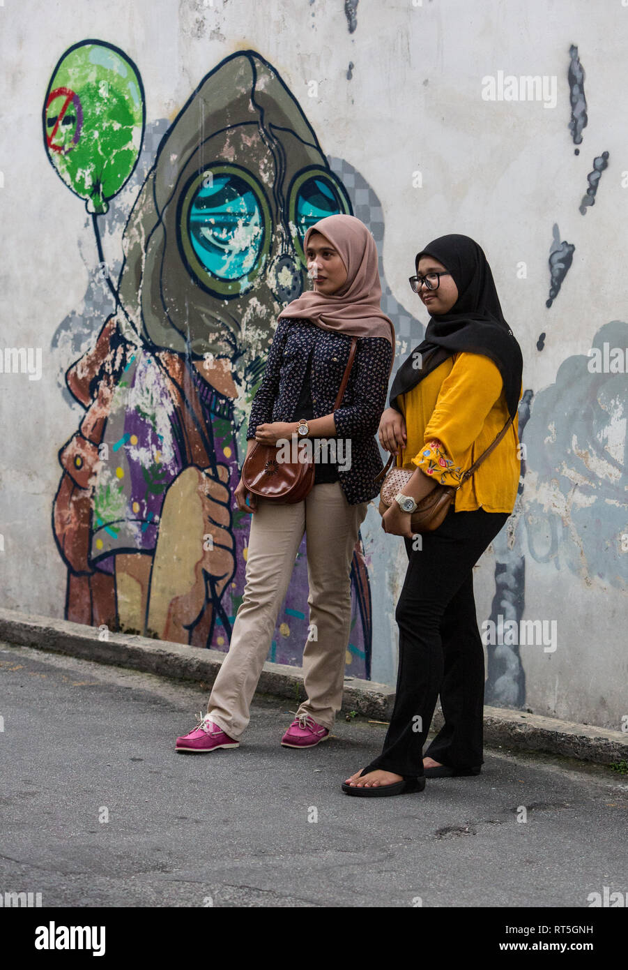 George Town, Penang, Malaysia.  Malaysian Women Posing in front of Street Art. Stock Photo