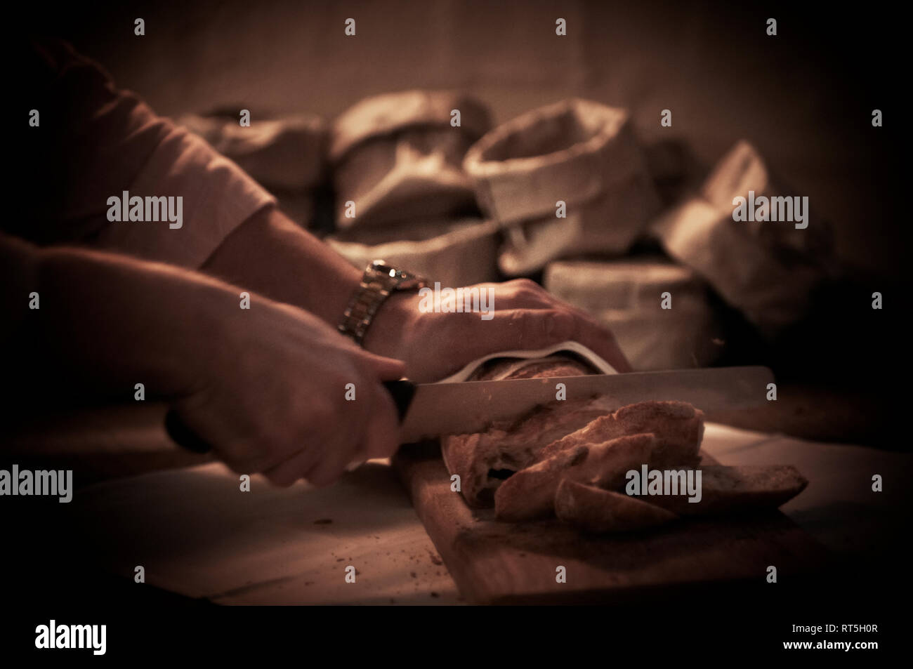 A pair of hands cut warm crusty bread for bread baskets in a fine