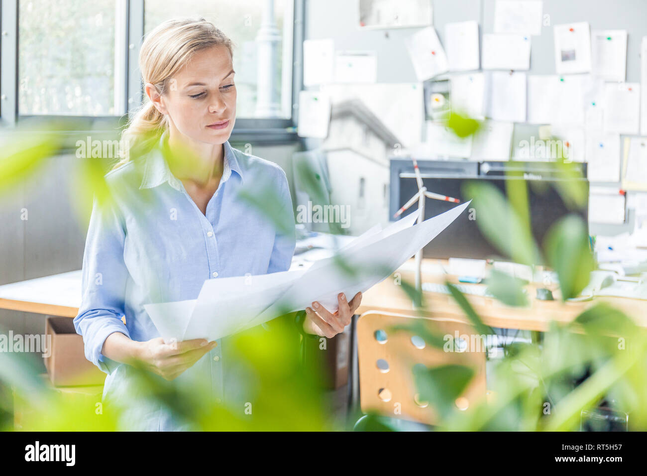 Woman in office working on plan with wind turbine model on table Stock Photo