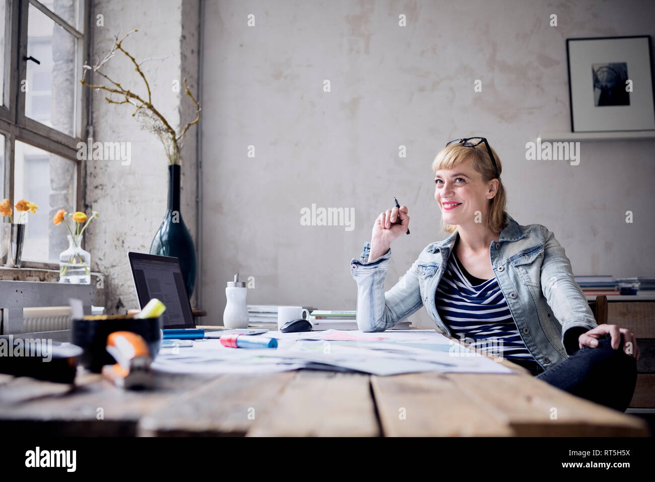 Portrait of laughing woman sitting at desk in a loft Stock Photo