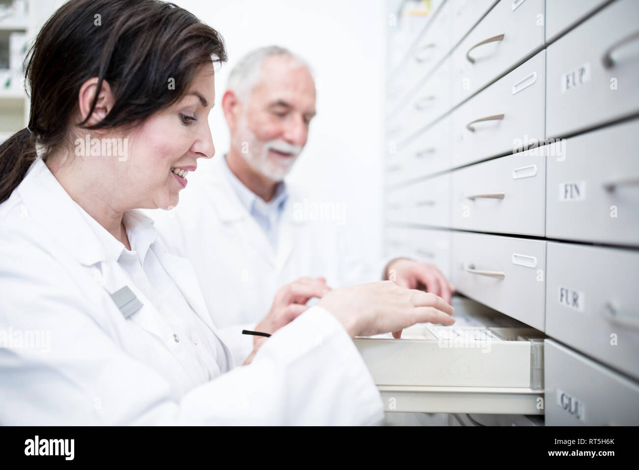 Two pharmacists at cabinet in pharmacy Stock Photo