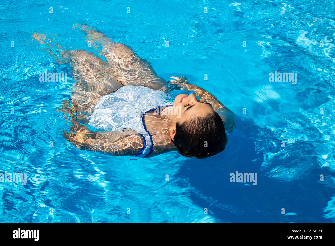 Young woman floating on water in swimming pool Stock Photo - Alamy
