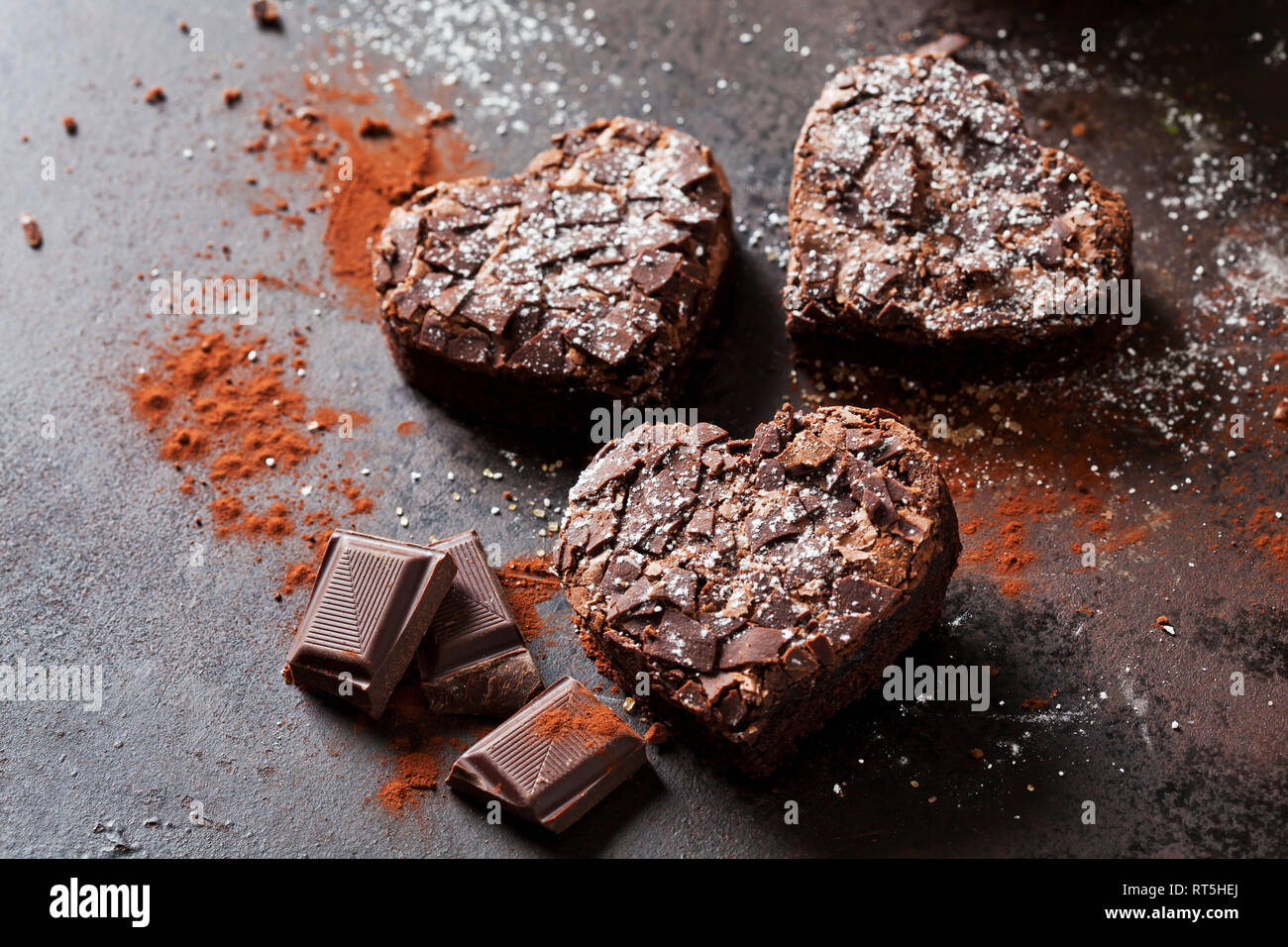 Three heart-shaped brownies and chocolate on metal Stock Photo