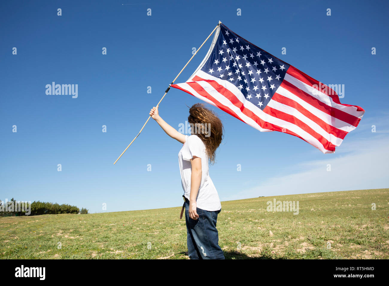 Girl holding American flag on field in remote landscape Stock Photo