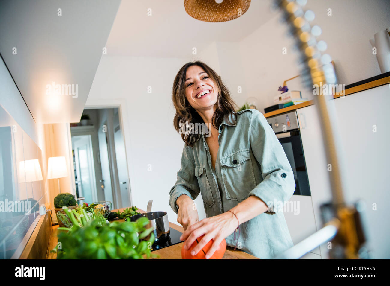 Laughing woman slicing pumpkin in her kitchen Stock Photo