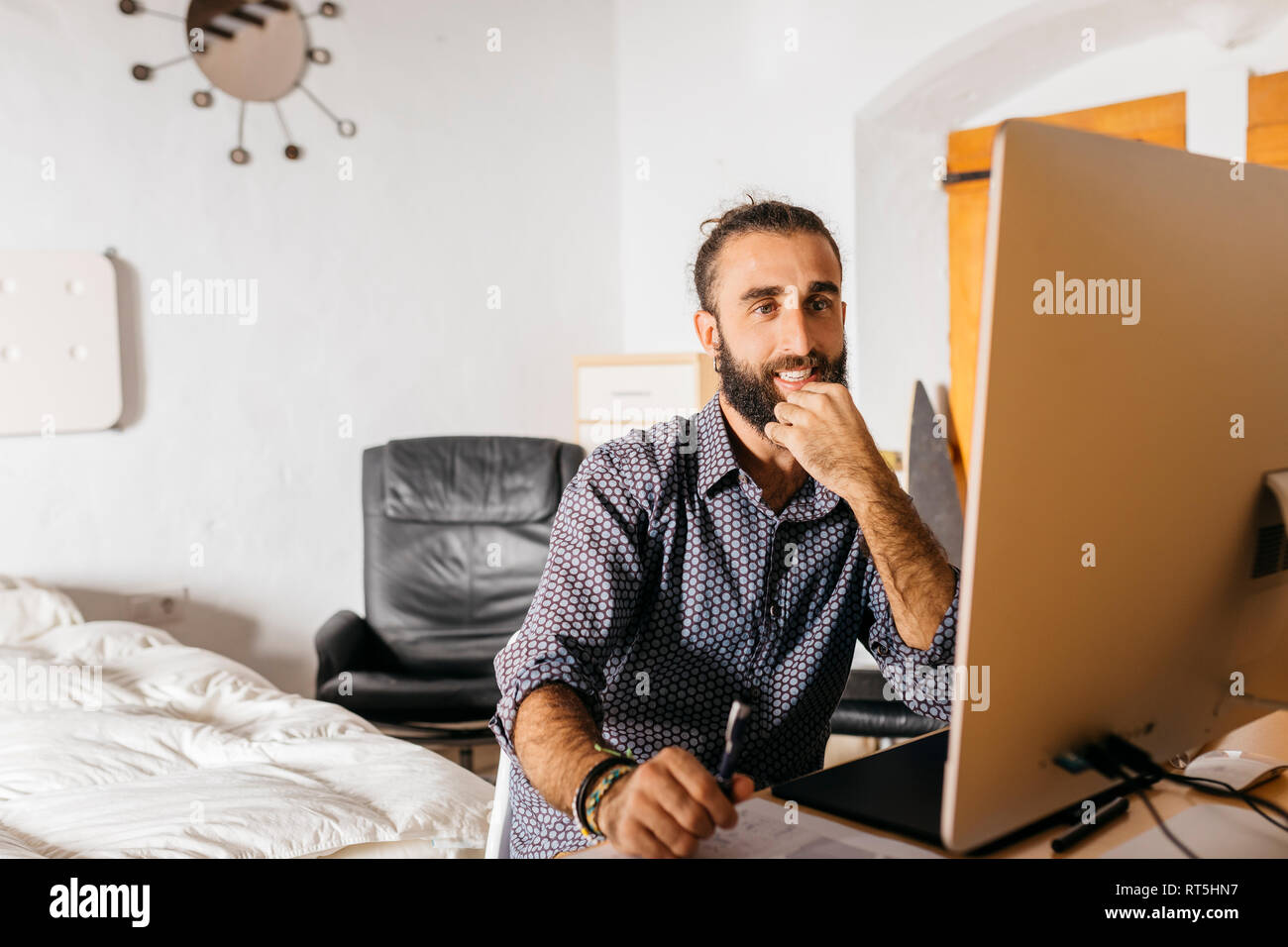 Smiling young man working at home using the computer Stock Photo