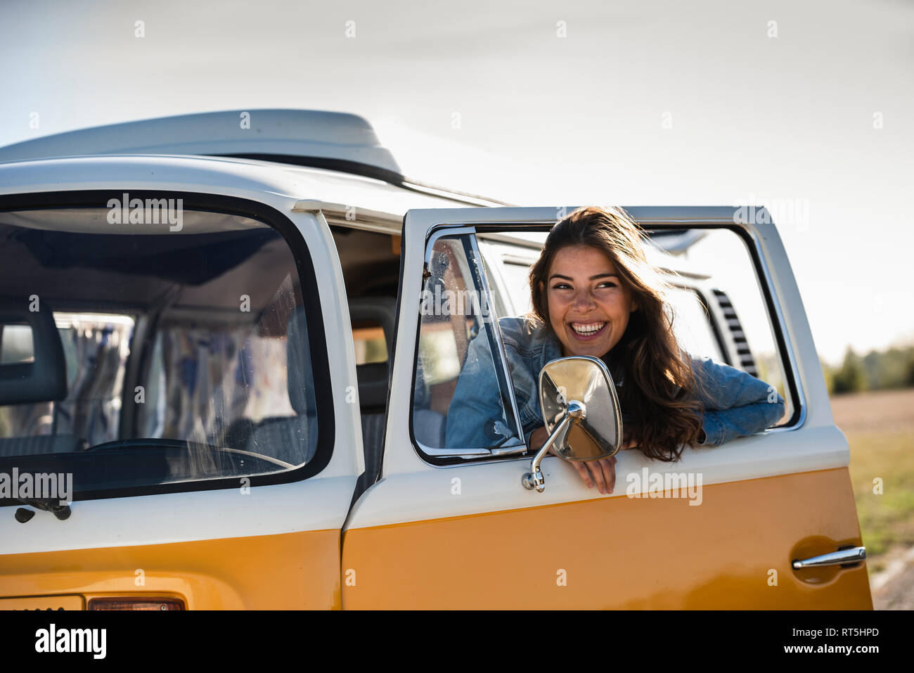 Pretty woman on a road trip with her camper, looking out of car window ...
