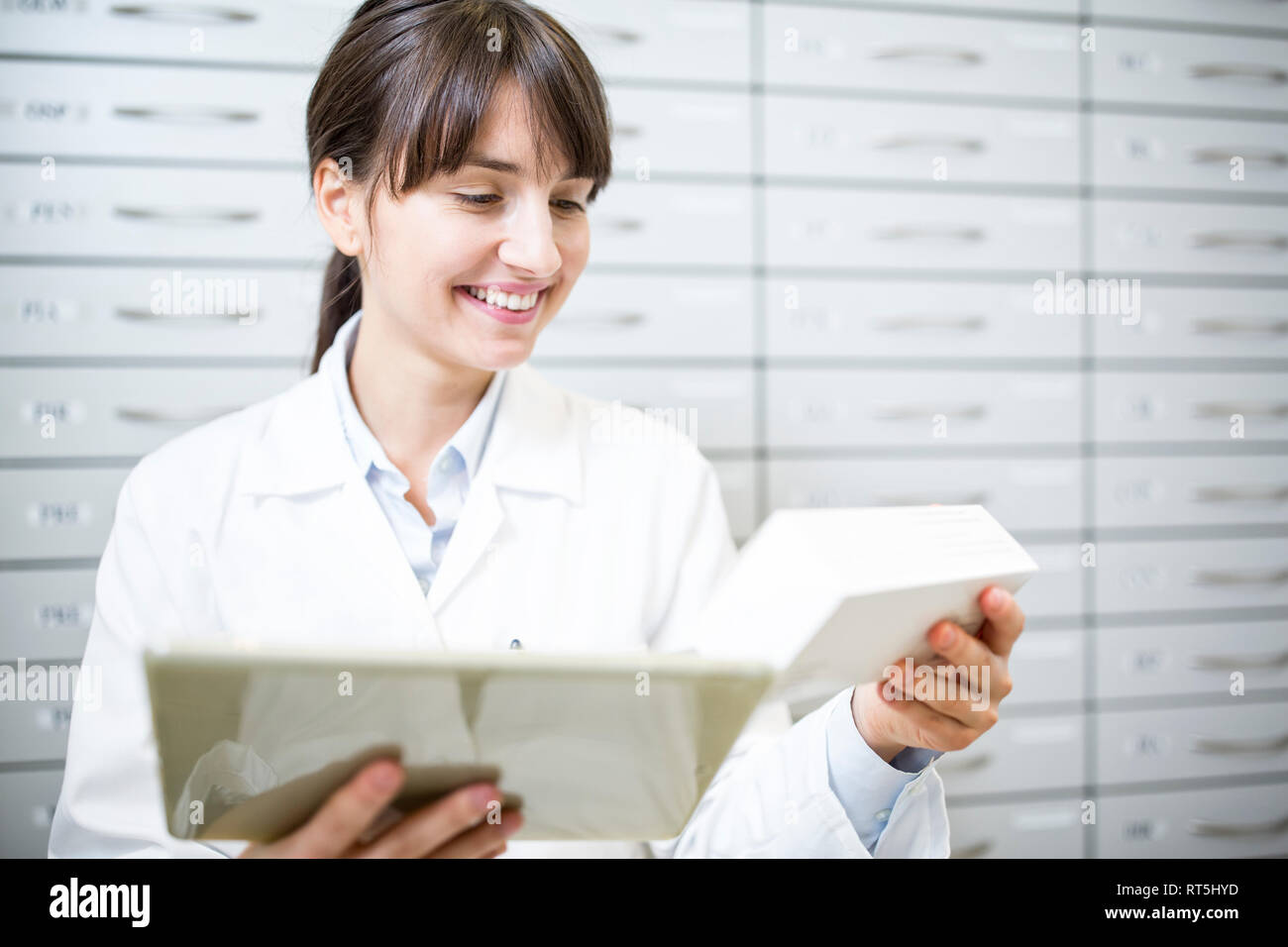 Smiling pharmacist with tablet and tablet package in pharmacy Stock Photo