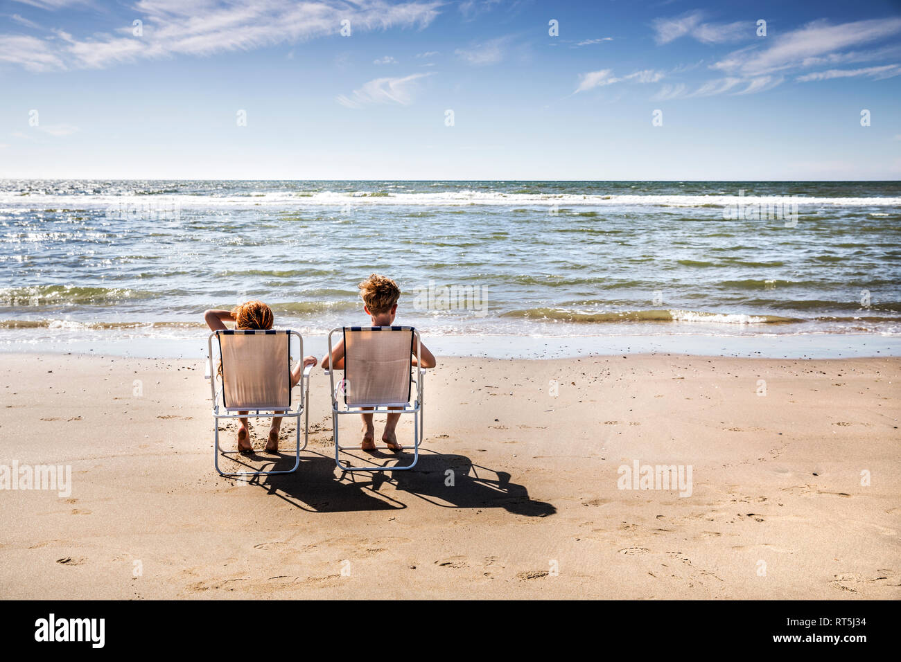 Netherlands, Zandvoort, boy and girl sitting on chairs on the beach Stock Photo