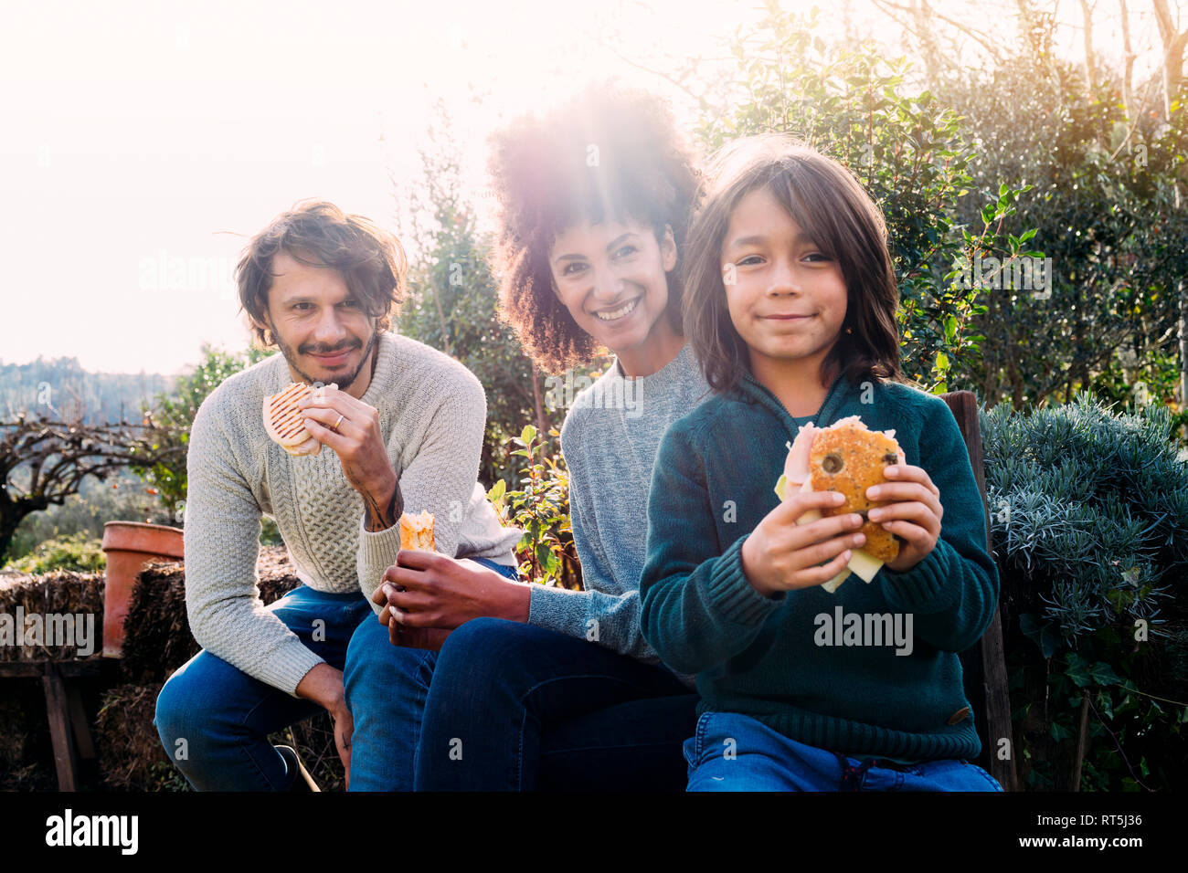 Happy family siting in garden, taking a break, eating sandwiches Stock Photo