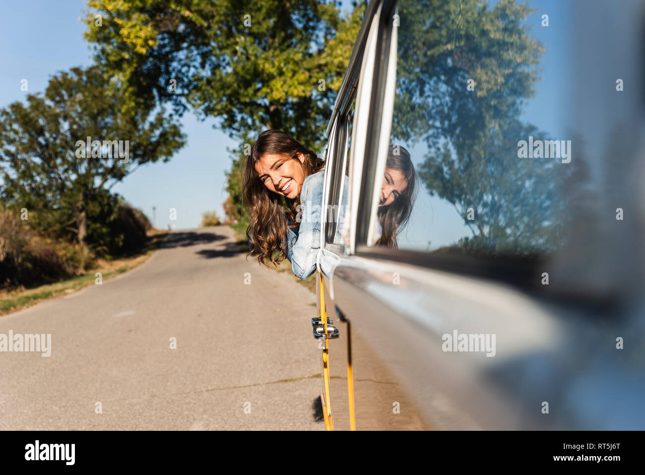 Pretty woman on a road trip with her camper, looking out of car window ...