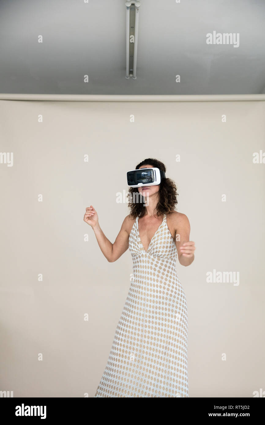 Woman wearing summer dress, dansing wwith VR goggles on Stock Photo