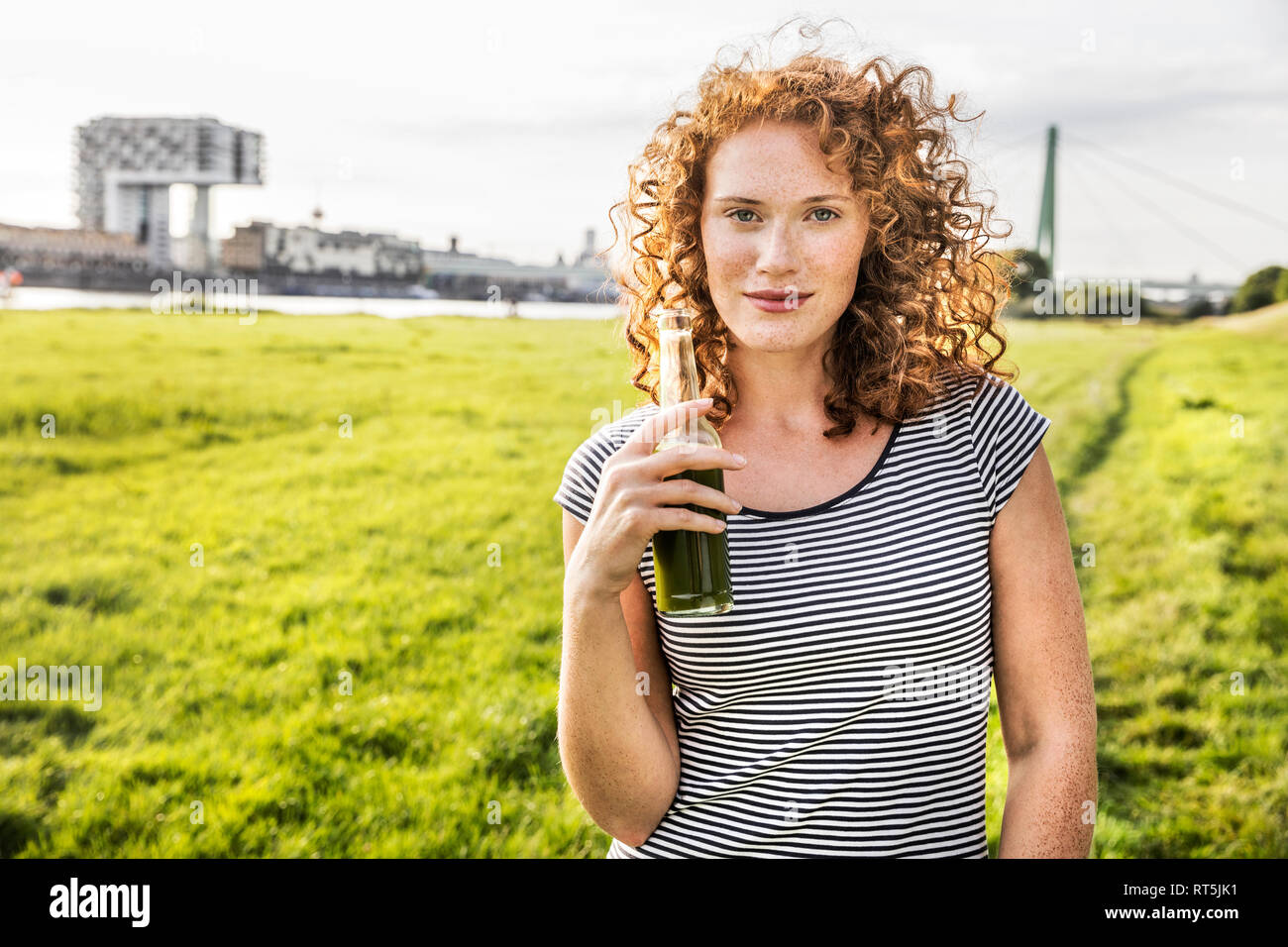 Germany, Cologne, portrait of redheaded young woman with beverage Stock Photo