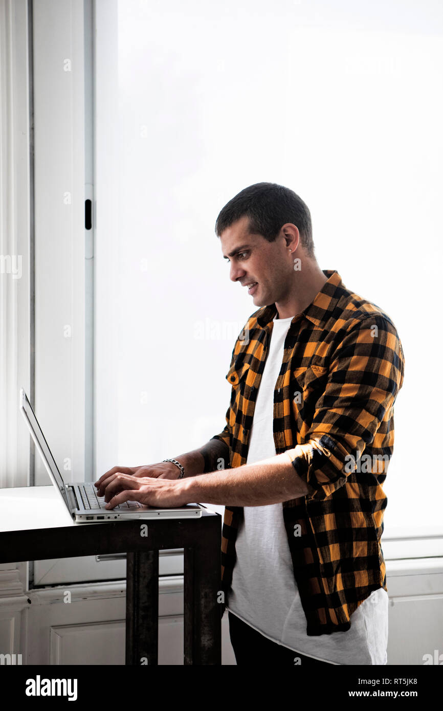 Smiling young man using laptop at table Stock Photo