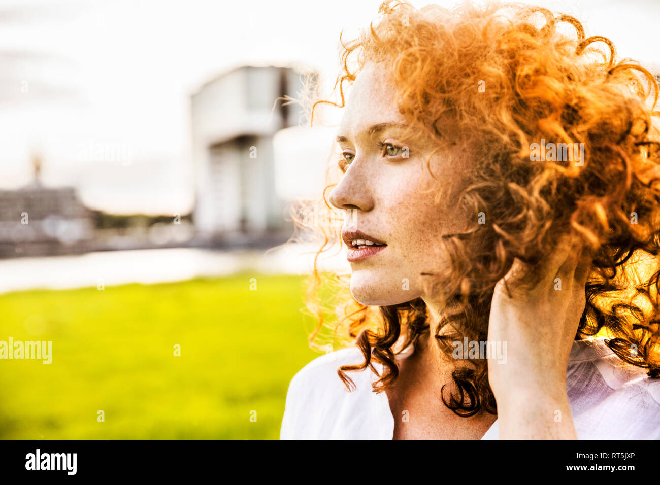 Germany, Cologne, portrait of freckled young woman with curly red hair Stock Photo