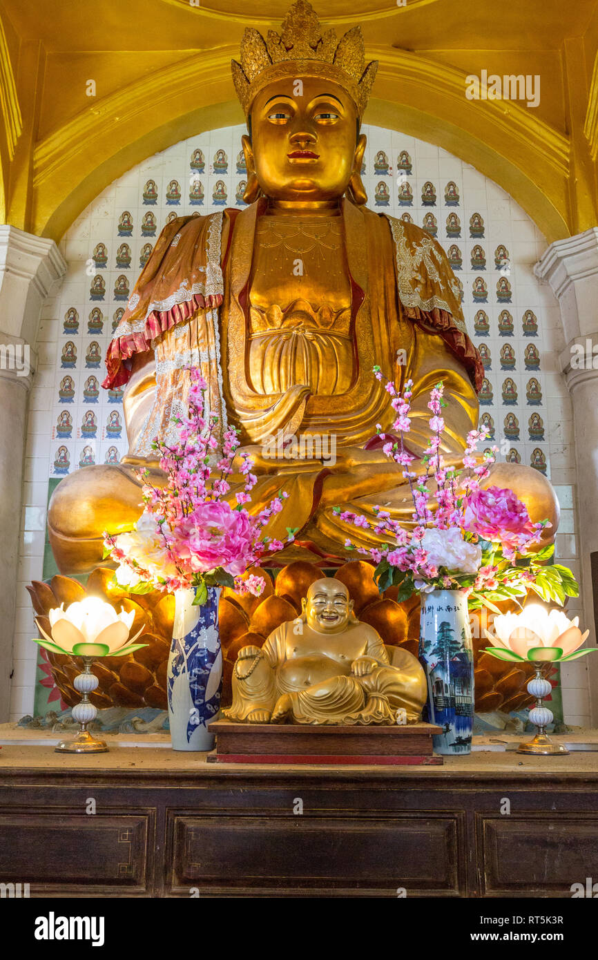 Chinese Buddha in the Ban Po Thar Pagoda, Kek Lok Si Buddhist Temple.  Small Smiling Buddha in foreground. George Town, Penang, Malaysia. Stock Photo