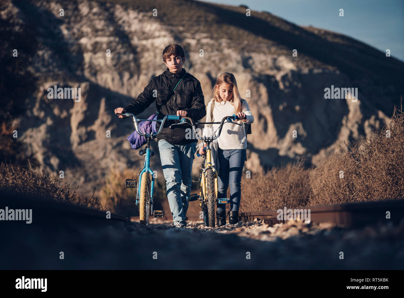 Boy and girl walking on the train track with bicycles Stock Photo
