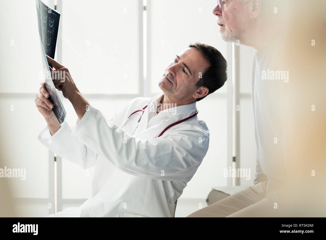 Doctor discussing MRT image with patient in medical practice Stock Photo