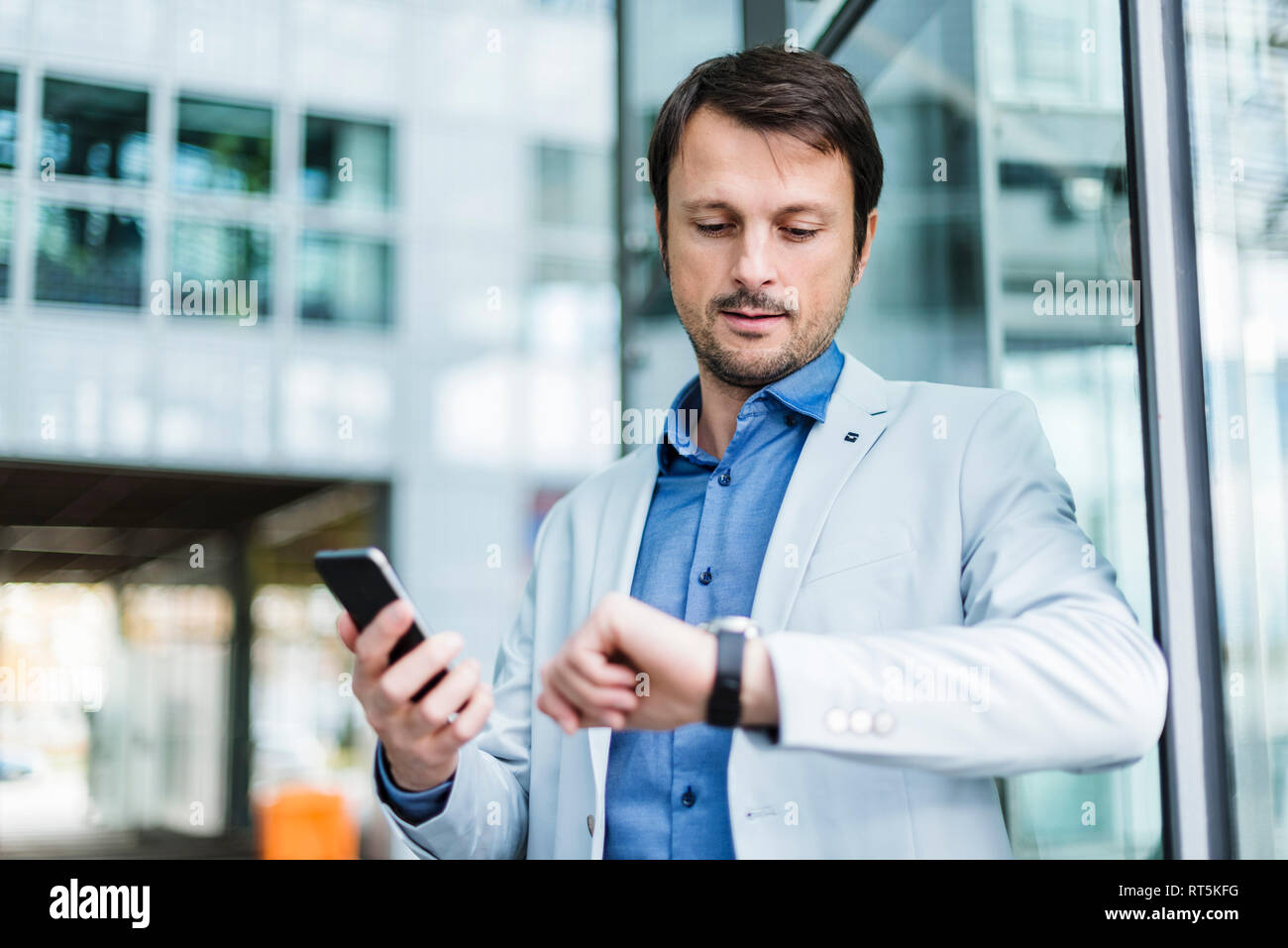 Portrait of a businessman checkin time, using smartphone Stock Photo