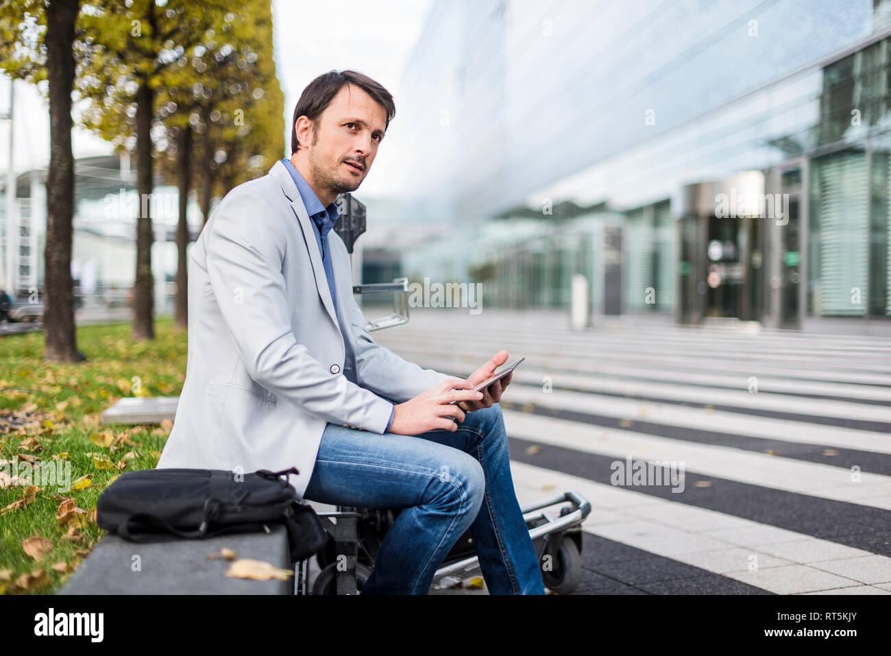 Businessman sitting on a bench, using digital tablet Stock Photo