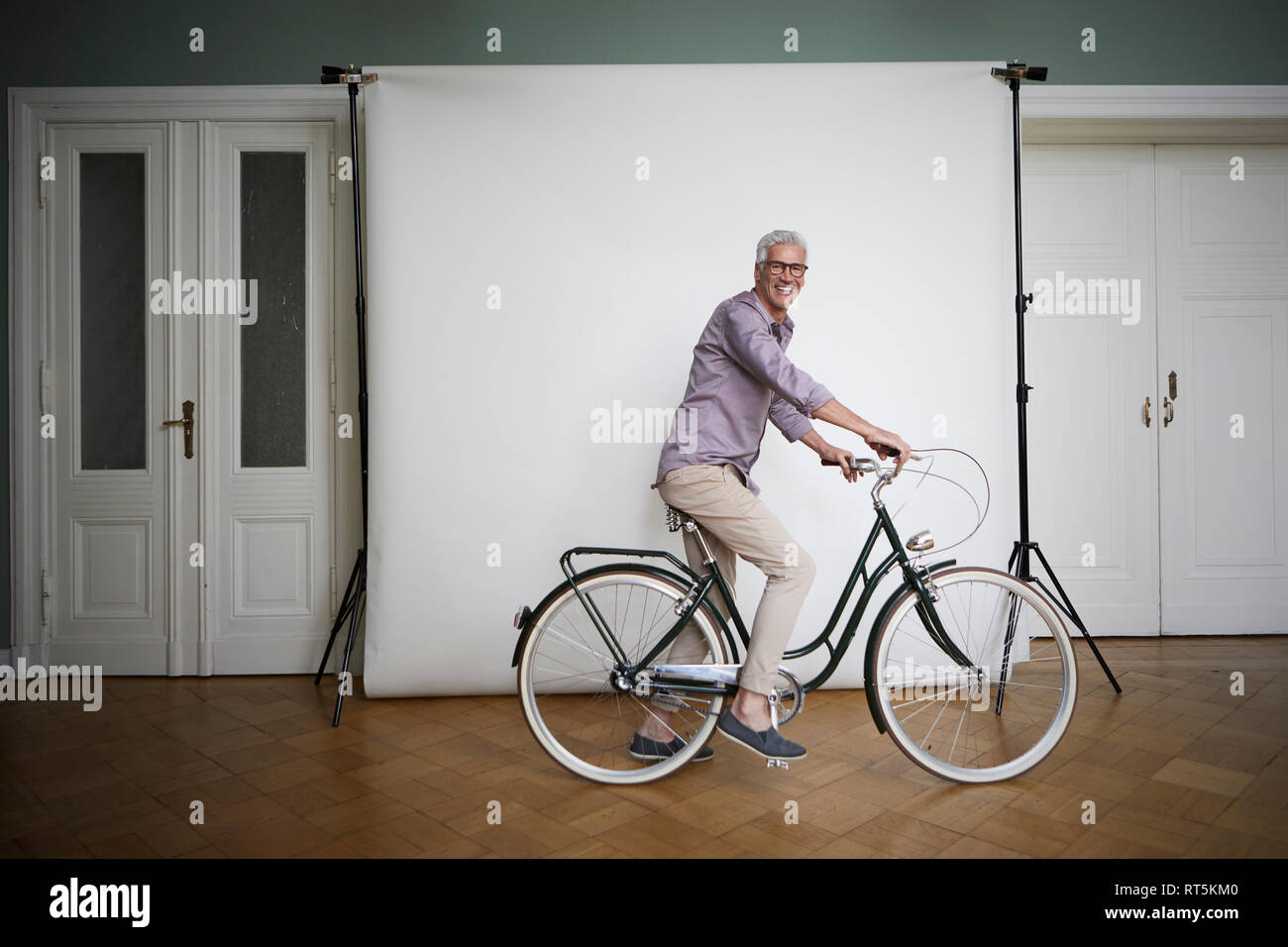 Portait of mature man posing on bicycle at projection screen Stock Photo