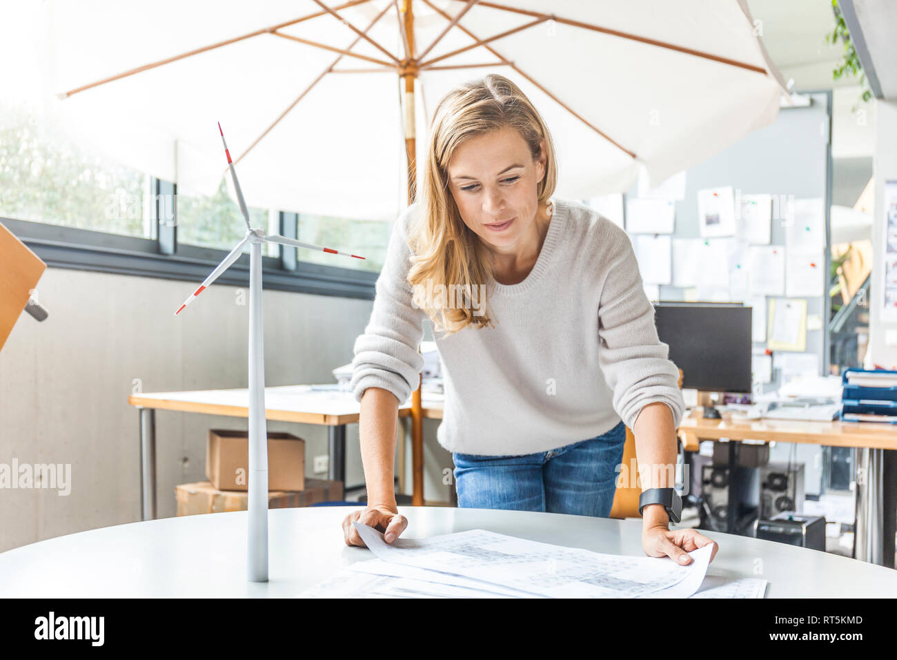 Woman in office working on plan with wind turbine model on table Stock Photo