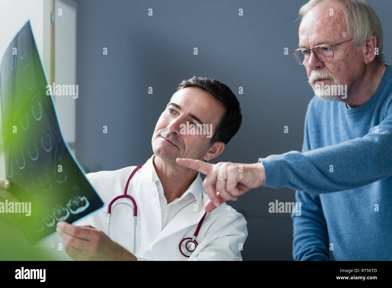 Doctor discussing MRT image with senior patient in medical practice Stock Photo