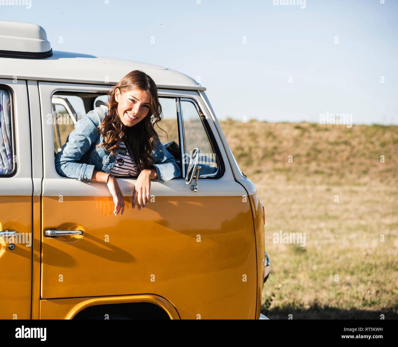 Pretty woman on a road trip with her camper, looking out of car window ...