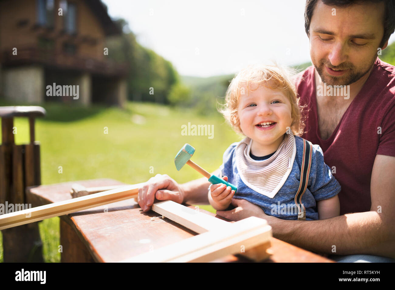 Father and little son working with hammer in garden Stock Photo