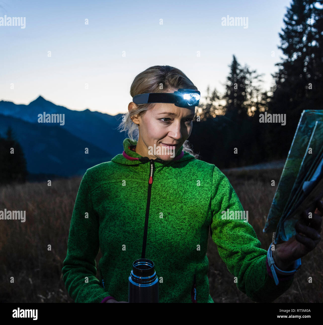 Hiking woman with head lamp, looking at a map Stock Photo