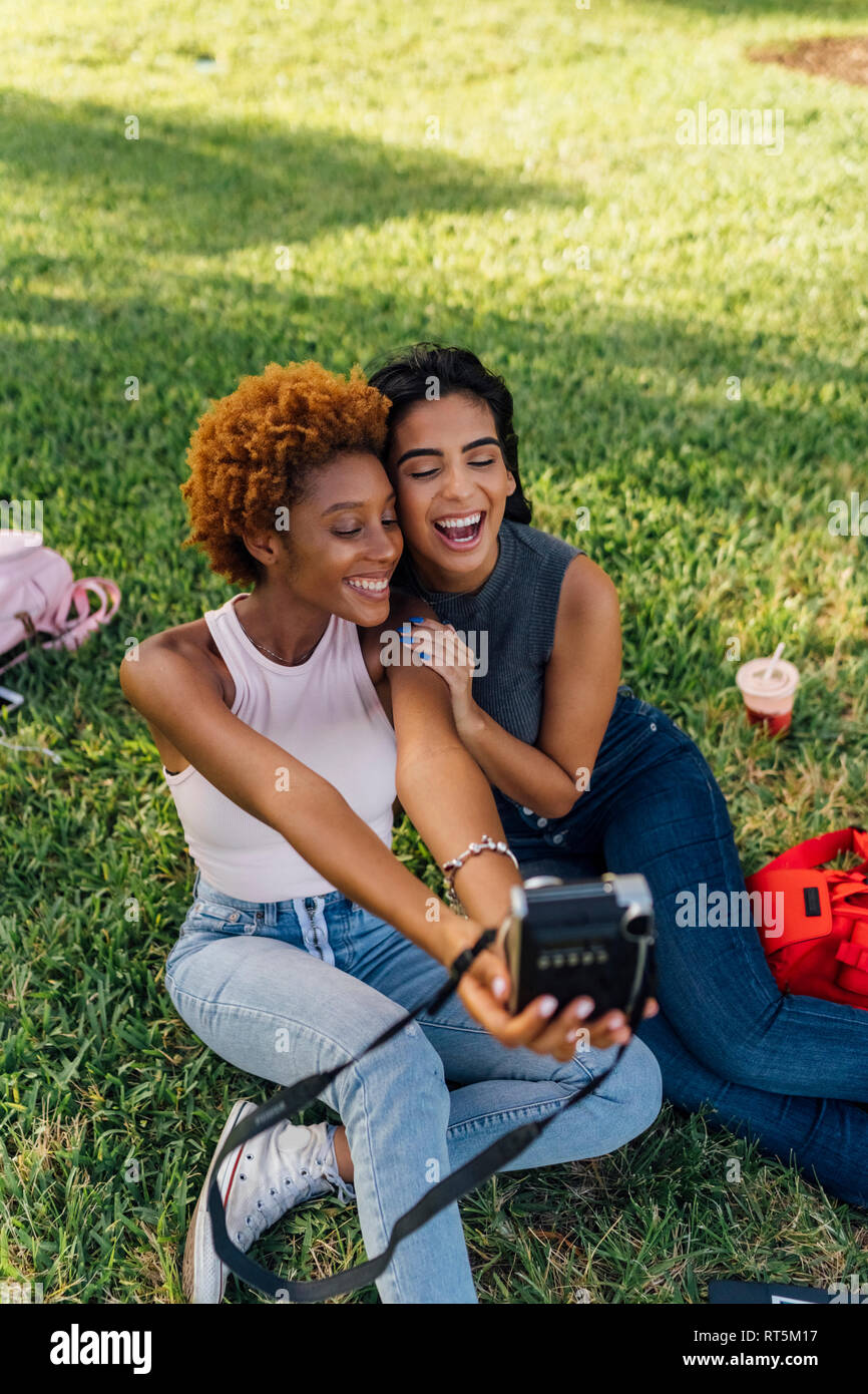 Two happy female friends taking an instant photo in a park Stock Photo