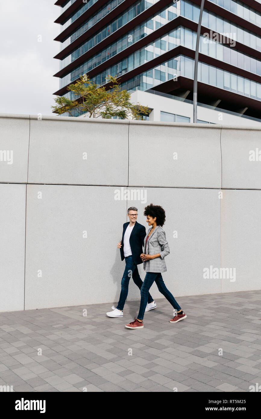 Two happy colleagues walking outside office building Stock Photo - Alamy