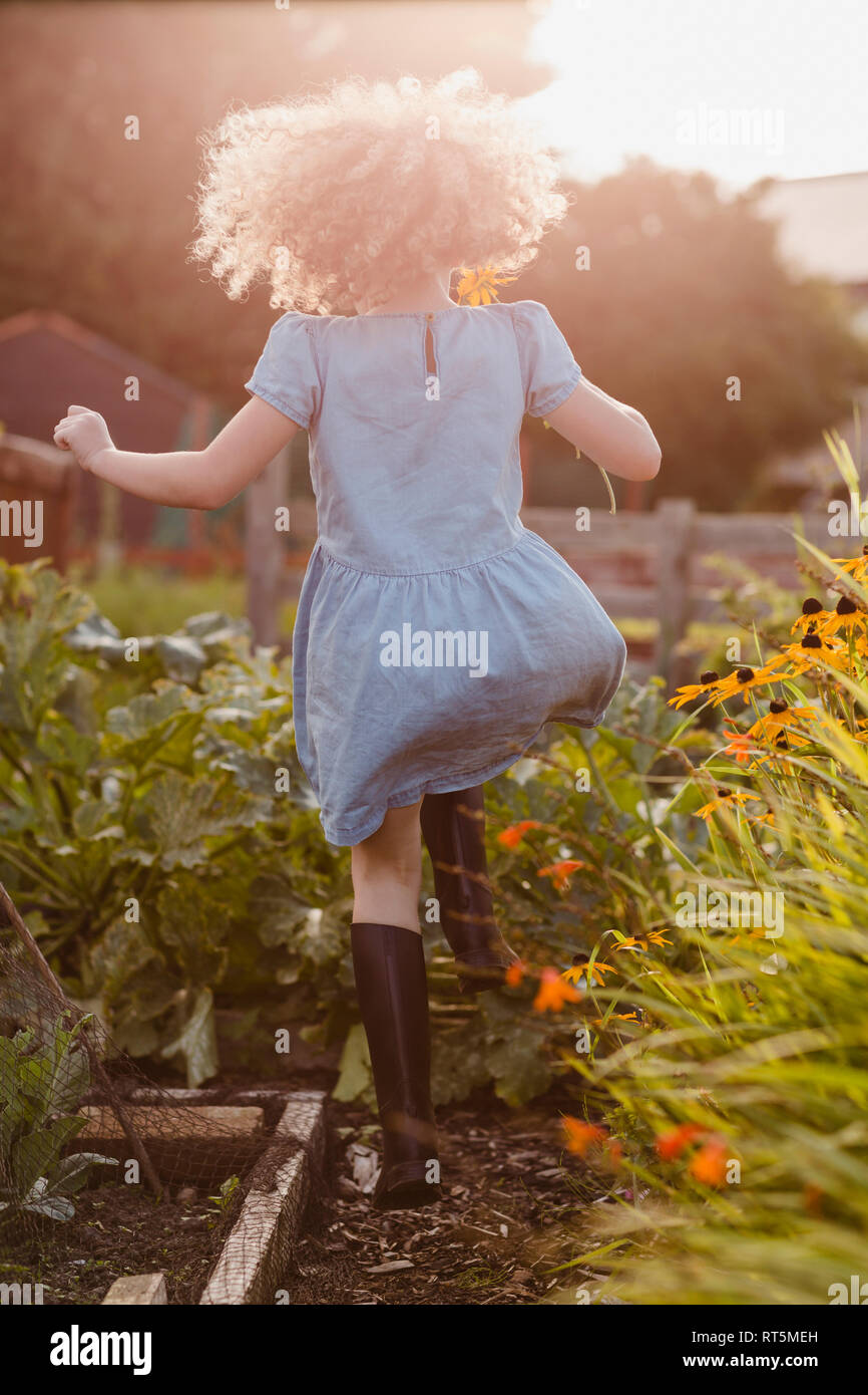 Back view of happy little girl jumping  in the garden Stock Photo