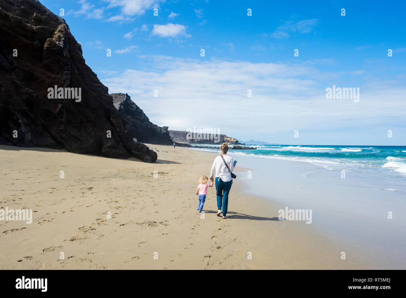 Spain, Canary Islands, Fuerteventura, La Pared, Playa del Viejo Rey, mother and daughter walking on the beach Stock Photo