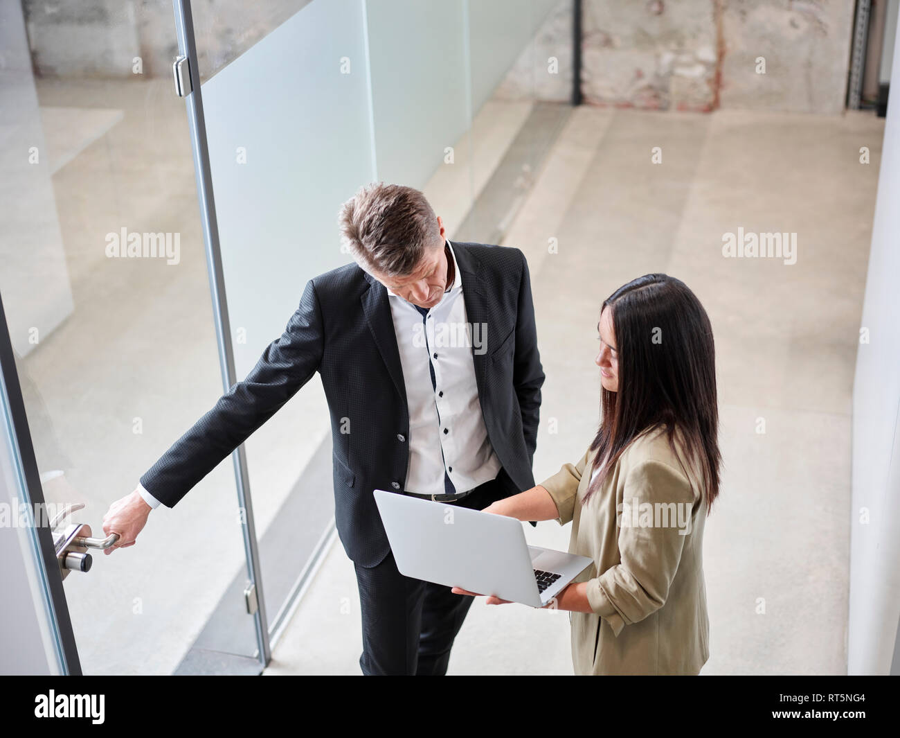 Businessman and businesswoman meeting with laptop at the door in office Stock Photo